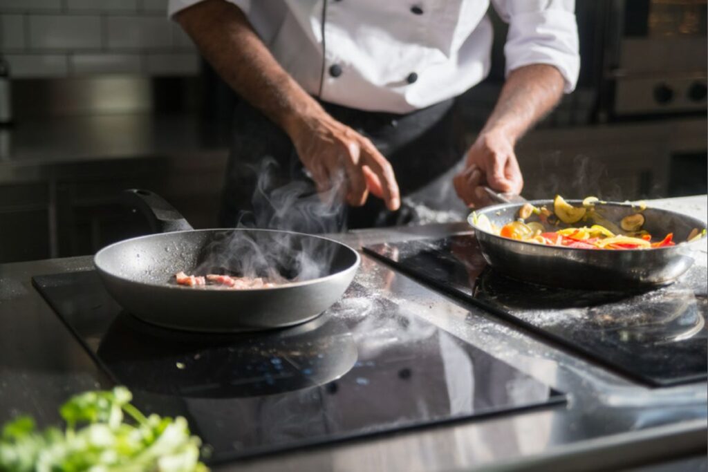 Chef preparando pratos com legumes e carne no fogão do reality Chef de Alto Nível