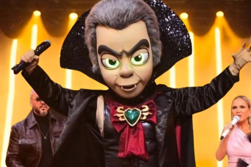 Ator Carmo Dalla Vecchia ao lado da fantasia de "Vampiro" do "The Masked Singer Brasil".