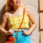 Mulher usando top amarelo de crochê com flores brancas