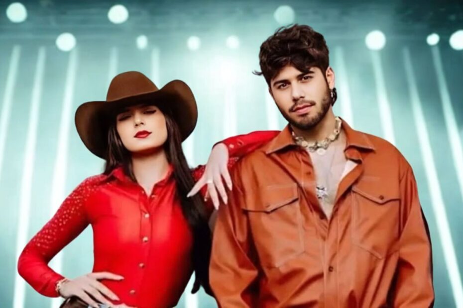 Ana Castela e Zé Felipe posando juntos em figurino country vermelho e laranja com iluminação de palco ao fundo